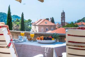 a table with a bowl of fruit and glasses of orange juice at Apartment Obradovic in Cavtat