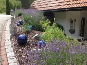 a garden with purple flowers and blue balls in a yard at Holzbildhauerei Kammerer in Triberg