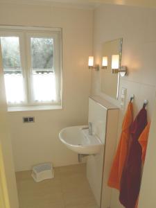 biała łazienka z umywalką i oknem w obiekcie Ferienhaus Kugelbake w mieście Cuxhaven