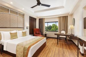 a hotel room with a bed and a desk at La Place Sarovar Portico in Lucknow