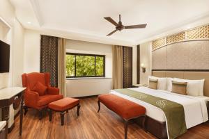 um quarto de hotel com uma cama e uma cadeira em La Place Sarovar Portico em Lucknow