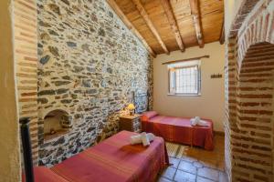 Cette chambre comprend 2 lits et un mur en pierre. dans l'établissement "El Porton" (El Borge ,Malaga)., à Borge