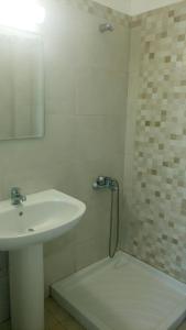 uma casa de banho branca com um lavatório e um chuveiro em Nefeli Apartments em Lefkos Karpathou