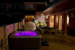 una bañera de hidromasaje con luces púrpuras en un patio por la noche en Csillag Panzió, en Vác