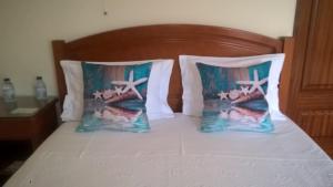 a bed with two pillows and two sandals on it at Residencial Idalio in Odemira