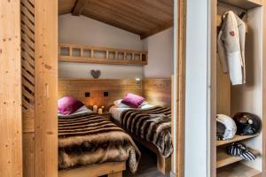 two beds in a room with wooden walls at Village Montana in Val Thorens