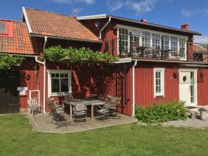 a red house with a table and chairs in the yard at Äventyrsgårdens Vandrarhem, Kinnekulle in Källby