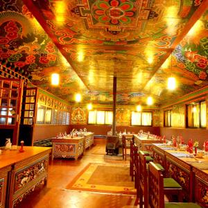 un restaurant avec des tables et des chaises et un plafond orné de peintures dans l'établissement Mountain Lodges of Nepal - Lukla, à Lukla