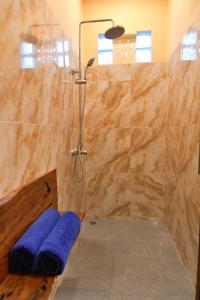 a bathroom with a shower with a blue towel at Paradise Palm Beach Bungalows and Dive Center in Tulamben