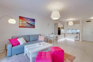 a living room with a blue couch and pink chairs at Apartament Crystal in Ustronie Morskie