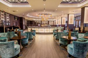a restaurant with blue chairs and a bar at Radisson Blu Edwardian Heathrow Hotel, London in Hillingdon
