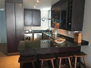 a kitchen with black cabinets and a counter with bar stools at Quayside 1001 Durban Point in Durban