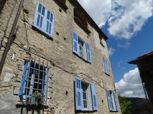 un antiguo edificio de piedra con ventanas con persianas azules en B&B Ududemà, en Dolcedo