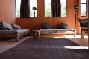 a living room with two couches and a rug at Tama Lodge in Mbour