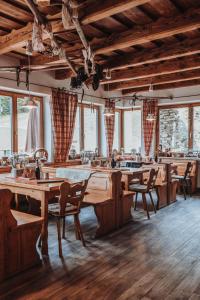 a restaurant with wooden tables and chairs and windows at Berggasthof Hochpröller in Sankt Englmar