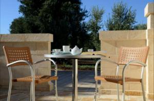 2 Stühle und ein Tisch auf der Terrasse in der Unterkunft Agriturismo Masseria San Leonardo in Savelletri di Fasano