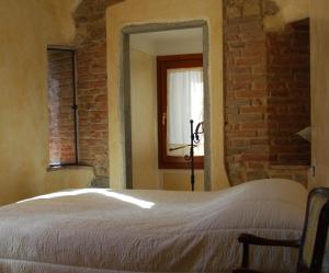 シーニャにあるIn Torreのレンガの壁の前にベッドが備わるベッドルーム1室