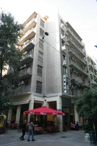 un gran edificio con una sombrilla roja delante de él en Alma, en Atenas