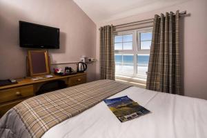 a bedroom with a bed and a television and a window at The Ship Hotel in Aberdaron