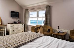 1 dormitorio con cama, escritorio y ventana en The Ship Hotel en Aberdaron