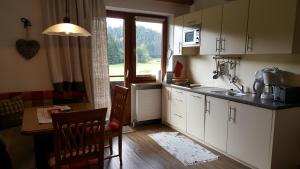 a kitchen with white cabinets and a table and a window at Ferienwohnungen Freundsheim in Kramsach