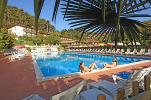 two women sitting in the swimming pool at a resort at Hotel Residence Campi in Tremosine Sul Garda