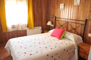 een slaapkamer met een bed met een roze kussen bij Alojamientos Rural Tejerina in Arroyo Frio