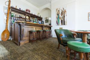 a bar with green chairs and a wooden bar counter at Hotel Balmoral in Bournemouth