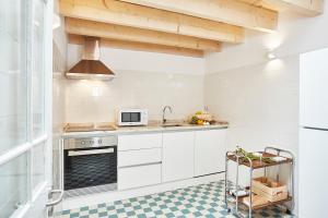 La cuisine est équipée de placards blancs et d'un four avec plaques de cuisson. dans l'établissement Fence Houses, à Coimbra