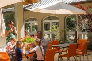 a group of people sitting at a table with an umbrella at VTF Le Bief Rouge in Métabief