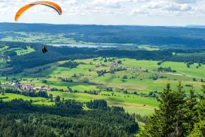 a paraglider is flying over a green field at VTF Le Bief Rouge in Métabief