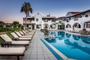 a pool with chaise lounge chairs next to a building at Villa Chantaloukas in Kokkini Khanion