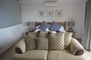 a couch with pillows on it in a room at Beach Retreat Guesthouse in Amanzimtoti