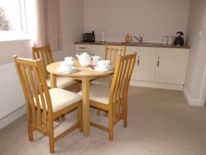 a wooden table and chairs with bowls and cups on it at Orchard View B&B in Whitminster