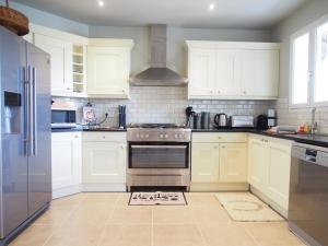 a kitchen with white cabinets and stainless steel appliances at La Villa a Chateau Franc-Daut Sleeps 6 in Saint-Magne-de-Castillon