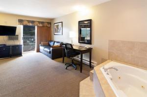 a hotel room with a desk and a bath tub at BCMInns - Coleman in Coleman