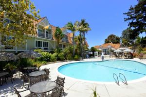 a swimming pool with tables and chairs next to a house at Best Western Premier Hotel Del Mar in San Diego