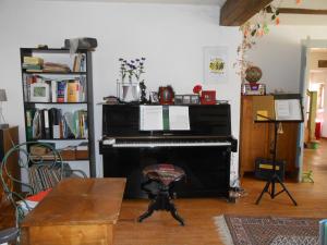 ein Wohnzimmer mit einem Klavier und einem Tisch in der Unterkunft Le Haut de l'Espérance in Uffholtz