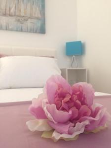 a pink flower sitting on a table next to a bed at Apartmani Porat Malinska in Malinska