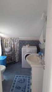 une salle de bains avec lave-linge et lavabo dans l'établissement Mansarda Camelie via dei Normanni, 45, à Campofelice di Roccella