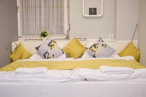 Una cama con almohadas amarillas y moradas. en Centrum Luxus Apartman en Makó