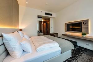 una camera da letto con un grande letto bianco e una televisione di Grid Hotel a Brno
