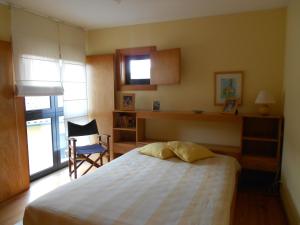 een slaapkamer met een bed, een stoel en een raam bij Casa do Murungal in Vila Praia de Âncora