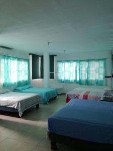 a large room with three beds and windows at Francisco Habitaciones in Manta