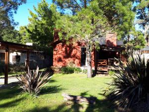 una casa de ladrillo rojo con un árbol en el patio en La Gringa, un espacio único en el medio del bosque, en Mar de las Pampas