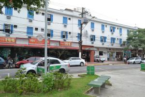 a building with cars parked in front of a street at Caiçara Hotel in Santos