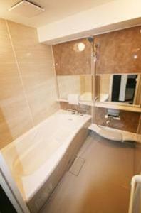 a bathroom with a bath tub and a sink at Weekly & Monthly City Inn Kokura in Kitakyushu