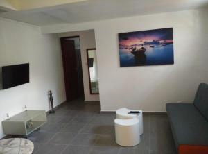 a living room with a couch and a tv at Gîte Acélie in Morne-à-lʼEau