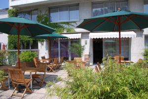 un patio avec des tables, des chaises et des parasols dans l'établissement Cit'Hotel Criden, à Tours