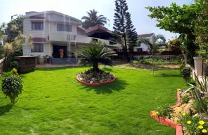 a house with a green yard with a palm tree at Urban Retreat Homestay in Mangalore